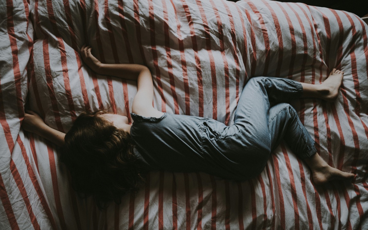 A restless person lying across a bed at night.