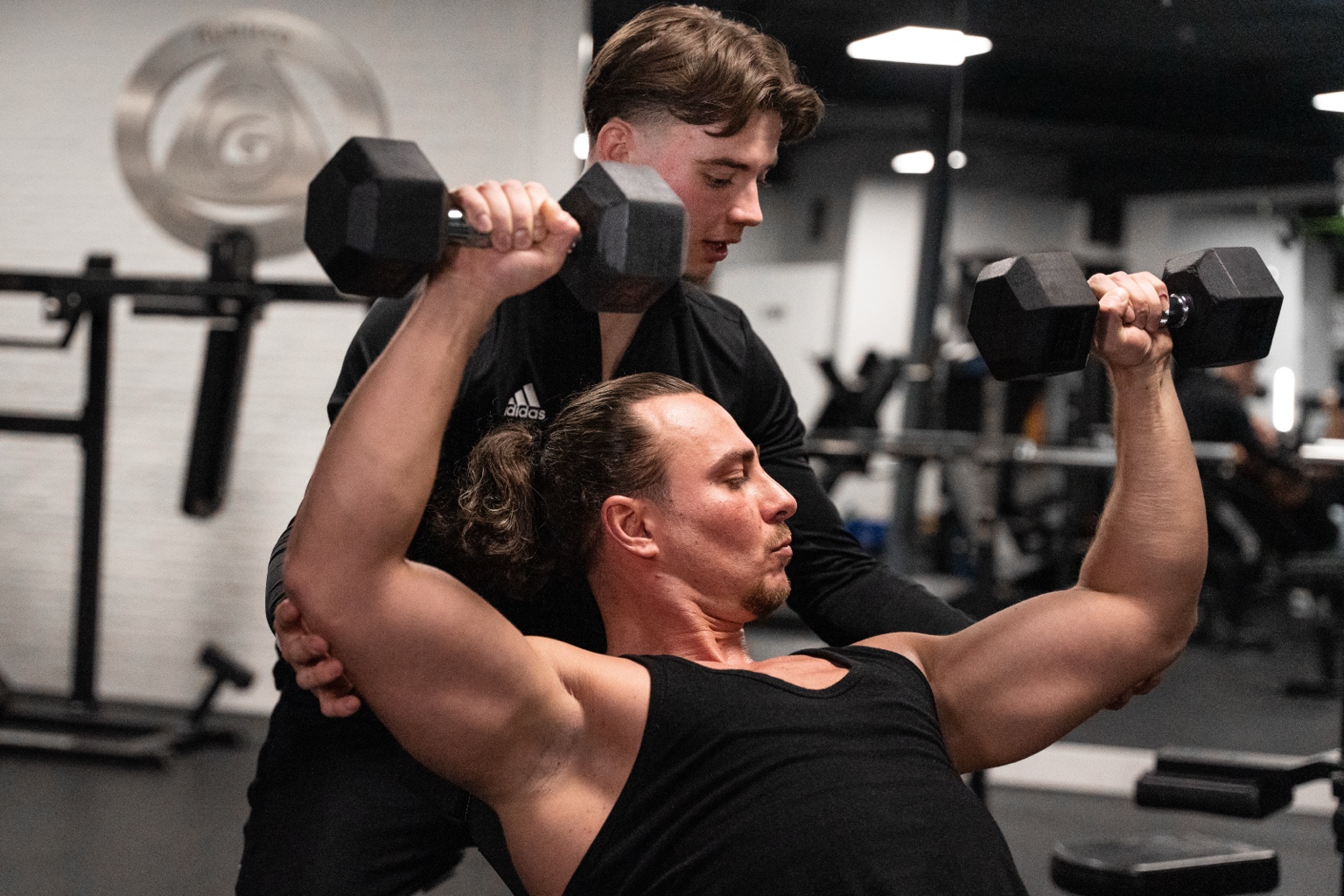 Robin Kramps supporting a client through a controlled dumbbell press